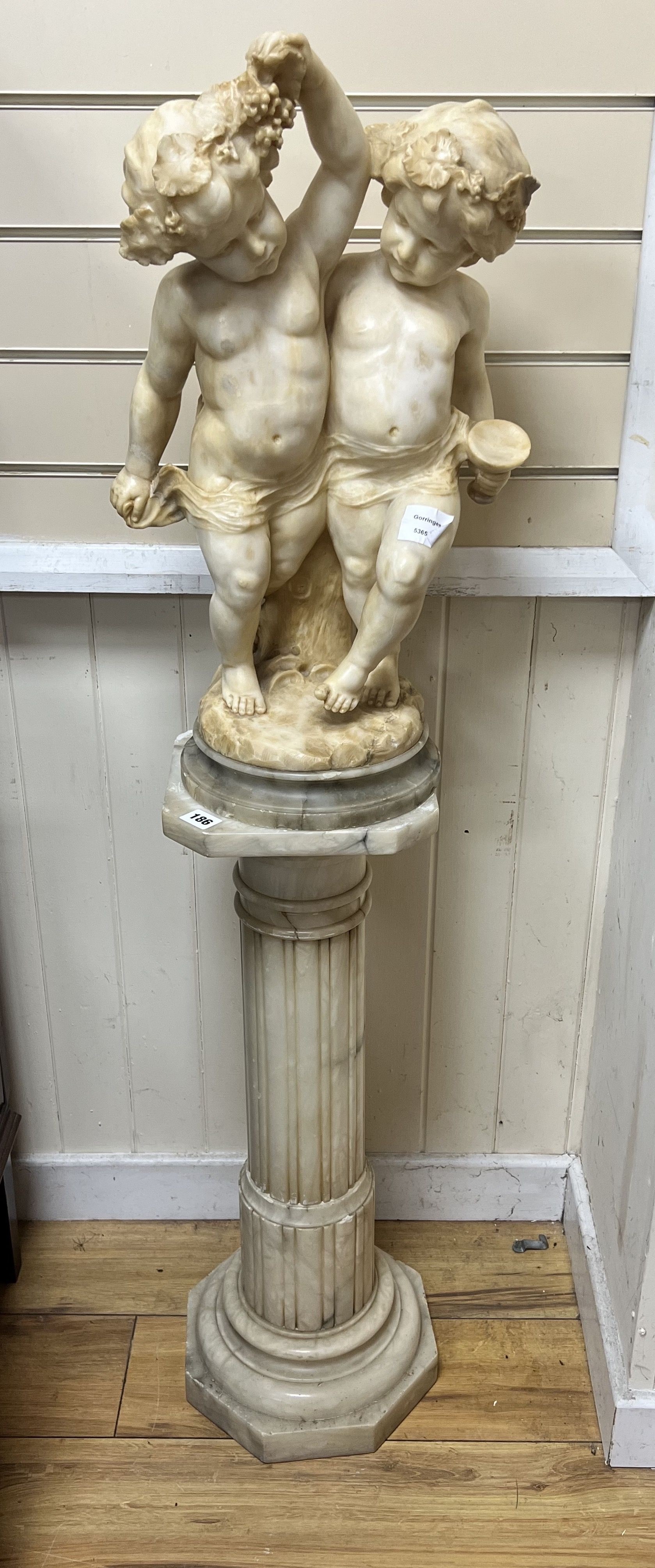 An Italian alabaster carving of bacchic cherubs on fluted pedestal, overall height 130cm